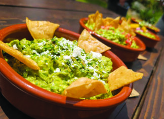 Oracles Unleashed Bowls of fresh guacamole topped with cheese and herbs and surrounded by tortilla chips.