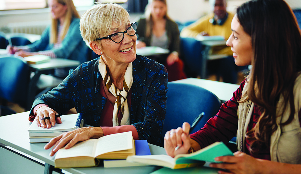 Smiling female adult learners during a class in a lecture hall.