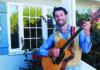 Rock the Porch Alt text: Santa Cruz Porchfest organizer Darrow Feldstein plays an acoustic guitar on a porch beside flowering roses.