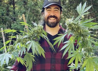 Weed Heaven Christopher Carr smiles while standing among mature cannabis plants