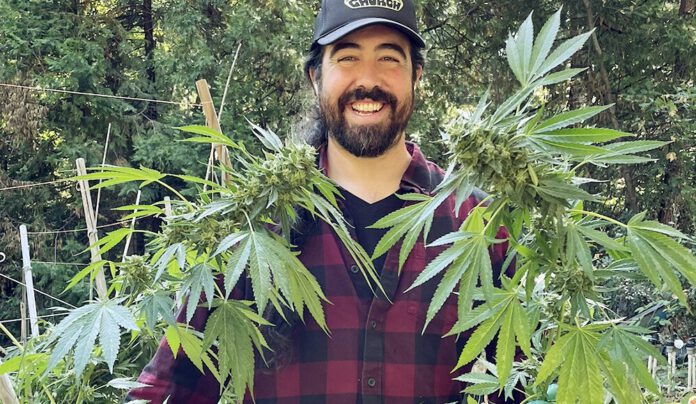 Weed Heaven Christopher Carr smiles while standing among mature cannabis plants