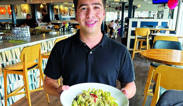 Main Beach Bites Luis Montoya holds a plate of pesto chicken penne inside Ideal Bar & Grill