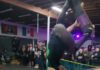 Grinding for a Great Cause A skater goes inverted above a wooden ramp as spectators watch at a Grind the Cause benefit.