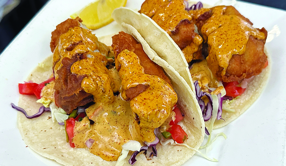 Battered fish tacos topped with shredded cabbage, diced vegetables and creamy orange sauce at The Clubhouse.