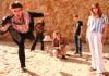 Smells Like Teen Spirit Five Coyote Theater band members pose on sand in front of a rocky bluff, with a camera and floor lamp as props.