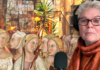 Lunch and Launch Kay Martin wears headphones and an orange scarf beside a microphone, against a collage of painted figures and travel scenes.