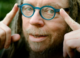 Reality, Remade Jaron Lanier points toward his round blue glasses in a close-up outdoor portrait.
