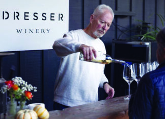 Berry Special A man pours white wine into a tasting glass for a guest at a counter beneath a Dresser Winery sign.