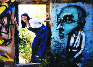 Haunting Santa Cruz Aubrey Graves leans through a doorway surrounded by colorful graffiti at the White Lady’s House in 1999.