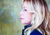 Things to do in Santa Cruz Rickie Lee Jones in profile, with long blonde hair and a dark jacket against a textured green wall.