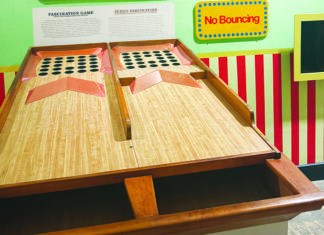 High Score Two wooden Fascination game lanes lead to grids of holes beneath a yellow “No Bouncing” sign at the MAH.
