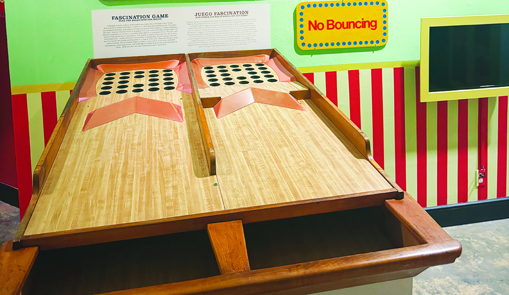 Two wooden Fascination game lanes lead to grids of holes beneath a yellow “No Bouncing” sign at the MAH.